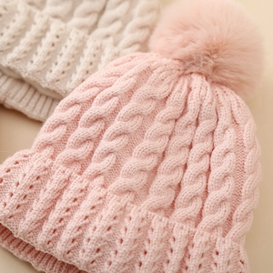 Winter infant knit beanies with cable patterns and soft faux fur pom-poms for warmth