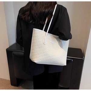 Detail showing the white woven texture and leather handles of the fashion tote bag