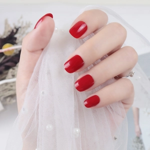 Short square-round glossy red press-on nails shown with elegant lace and flower decor