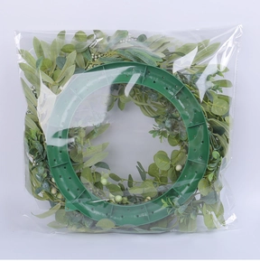Detail view of a lush artificial eucalyptus wreath packaged in a clear protective plastic bag
