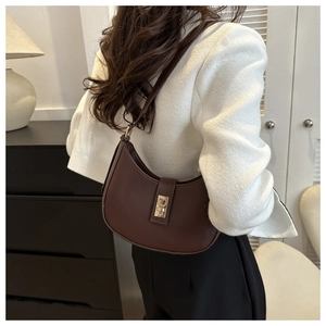 Detail of a brown leather crescent hobo bag with gold hardware worn by a model