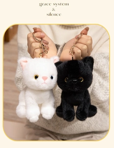 Detail of plush cat keychains in black and white with golden metal lobster clasps
