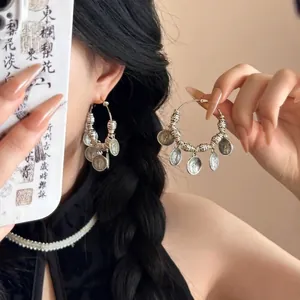 Gros plan détaillé de boucles d'oreilles bohèmes argentées avec breloques pièces vintage