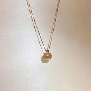 Détail d'un pendentif carré en œil de chat sur une fine chaîne en acier doré