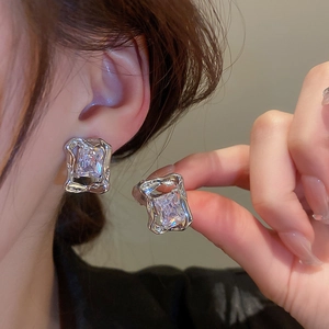 Close-up of molten silver rectangular earrings with large crystal stone on model