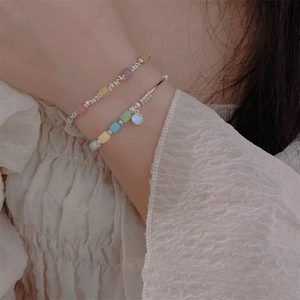 Detail of layered colorful beaded bracelet and silver bangle with moonstone pendant
