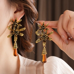 Detail of vintage flower earrings with amber water drop pendants in retro gold finish