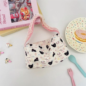 Detail of quilted canvas tote with cute cartoon patterns and pink lace-trimmed handles