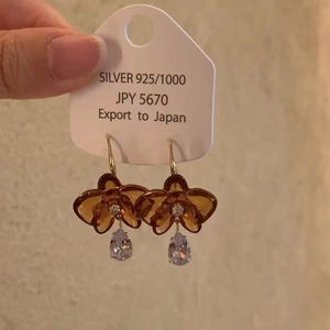 Détail macro des boucles d'oreilles fleur en argent 925 et résine ambre avec cristal