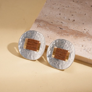Detail of silver hammered metal stud earrings with dark brown leather wrap on stone