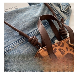 Detail of leopard print crossbody bag with knotted faux leather strap and metal magnetic snap