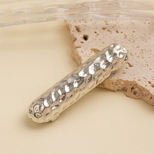 Close-up of a silver hammered metal hair clip on a natural stone background