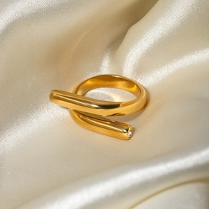 Detail of 18k gold plated criss-cross ring with crystal on soft beige silk fabric