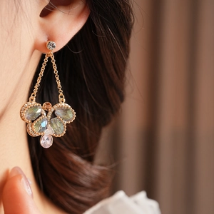 Macro shot of vintage style gold earrings with multicolored crystal pendants on ear