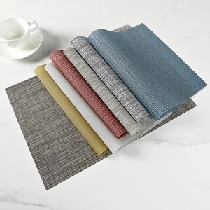 Woven PVC heat-resistant placemats set in various colors on marble table surface