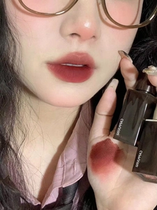 Detail showing dark red berry lip glaze swatches on lips and hand with matte finish