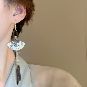 Détail d'une boucle d'oreille en forme d'éventail avec bambou et longs glands gris