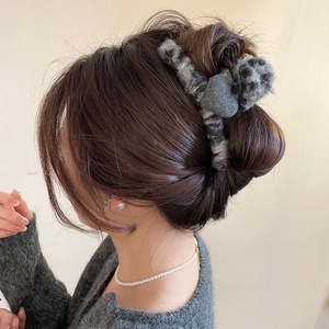 Vue détaillée d'une pince à cheveux en peluche léopard avec un décor de cœur gris sur chignon