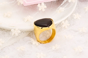 Detailed view of a wide gold ring featuring a polished band and a black heart gemstone