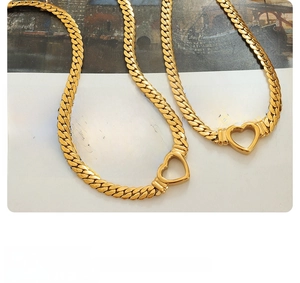 Gros plan de colliers à maille cubaine dorée avec pendentifs cœur évidé sur livre ancien