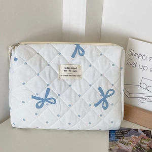 Detail of quilted white cosmetic bag with blue polka dots and soft cotton texture