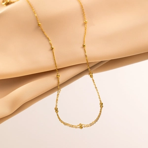 Elegant 18K gold-plated beaded necklace displayed on soft beige silk fabric