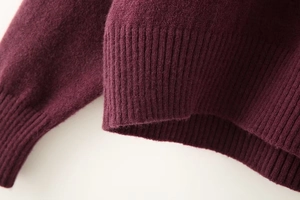 Close-up of soft burgundy knit sweater featuring premium ribbed cuff and plush texture