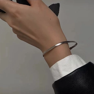 Detail of silver snake bone chain bracelet worn on wrist showing minimalist metal texture
