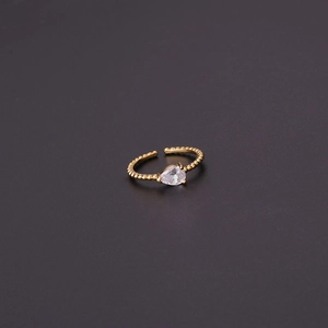 Detailed view of teardrop zircon ring with golden beaded band on dark gray background
