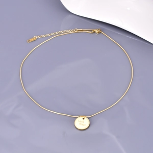 Detail view of gold stainless steel necklace with round pendant engraved Luck 4ever