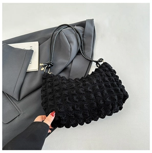 Detailed texture of black bubble pleated fabric on a minimalist cloud shoulder bag