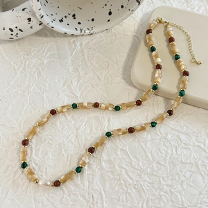 Detail of beaded shell necklace with champagne pearls, green stone and gold extender chain
