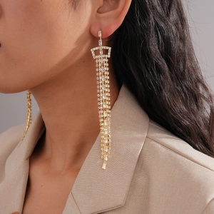 Close-up of model wearing gold tassel earrings with white zircon diamonds and metal fringe