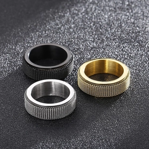 Detail of three rotating mesh texture titanium rings in gold, black and silver finishes