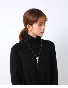 Silver flower necklace with sparkling rhinestones and tassels on a black knit sweater
