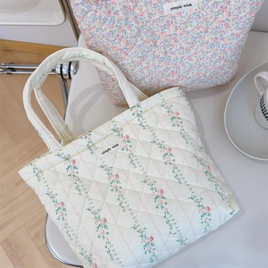 Detail of floral quilted cotton tote bags with simple wish label on white table