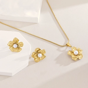 Detail of gold camellia necklace and stud earrings set with elegant white pearls