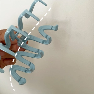 Macro view of light blue wave-shaped hair claw clip showing curved plastic teeth