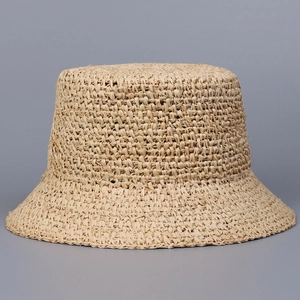 Macro detail of hand-woven raffia texture on a beige flat top straw fisherman hat