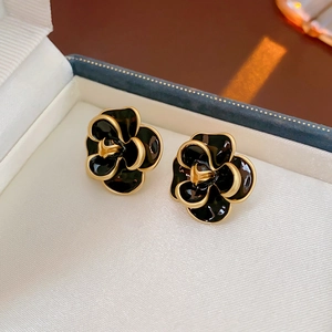Macro shot of vintage black camellia earrings with gold trim in a premium jewelry box