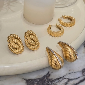 Detail of vintage 18k gold plated twist earrings and zircon studs on ceramic tray