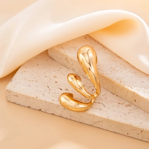 Detailed view of polished gold sculptural ring on silk fabric and stone display