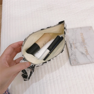 Vue détaillée d'une mini pochette en tissu fleuri montrant le rangement pour cosmétiques