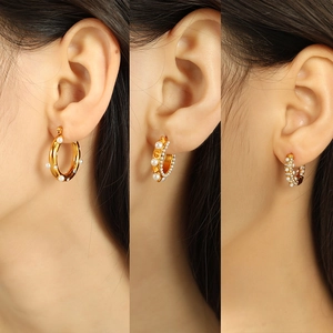 Three styles of gold C-shaped hoop earrings with pearls and crystals on ear