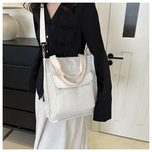 Detail shot of white corduroy tote bag showing ribbed texture and front flap pocket