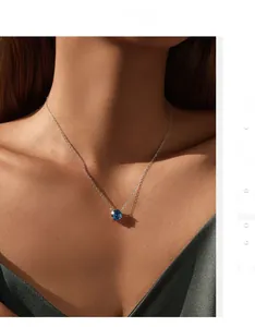 Macro view of blue round gemstone pendant on a silver S925 necklace worn by model