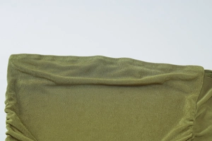Detailed close-up of green ribbed knit fabric showing soft texture and elastic pleats