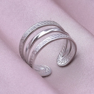 Macro view of layered silver stainless steel adjustable ring on pink silk fabric