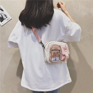 Detail of pink and white crossbody bag with transparent window and floral charm accessory