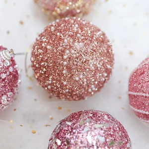 Close-up of pink Christmas ornaments with sequins and pearls on white soft tulle fabric